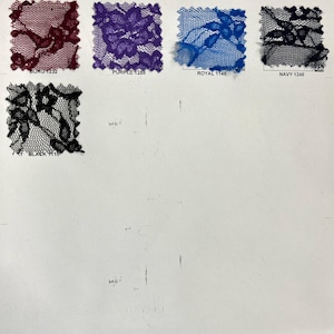 May include: A selection of lace fabric samples in shades of burgundy, purple, royal blue, navy, and black. Each square swatch displays a detailed floral design. The colour names are printed beneath each sample.