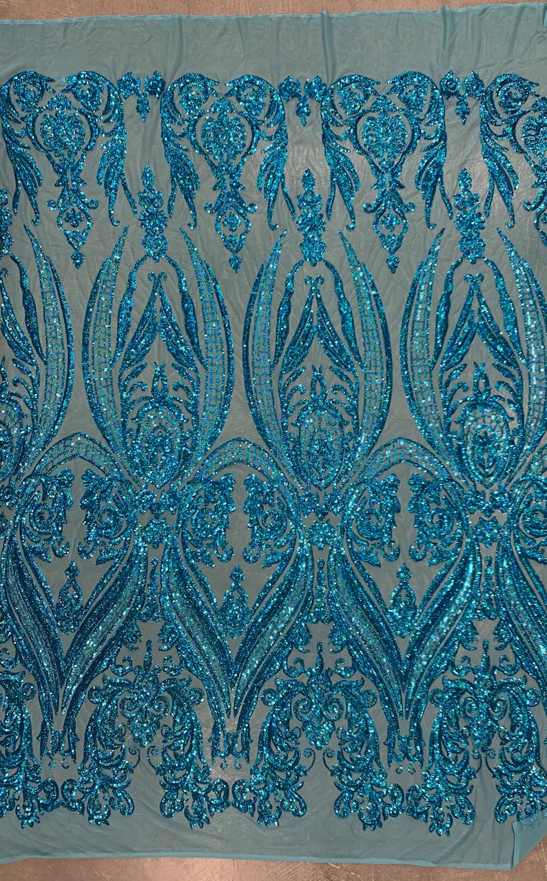 Puede incluir: Tela de lentejuelas azul turquesa con un patr&oacute;n de damasco. Las lentejuelas son iridiscentes y tienen un acabado brillante.