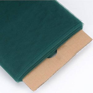 Può includere: Un rotolo di tulle verde scuro su un supporto di cartone marrone.