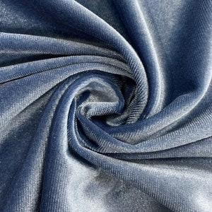 May include: Close-up of a soft, blue velvet fabric with a subtle ribbed texture. The fabric is folded and draped, showcasing its luxurious feel.