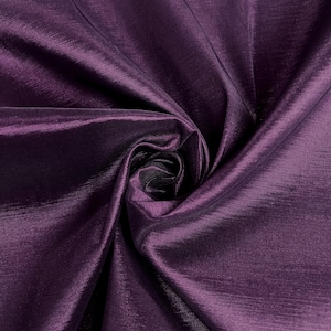 May include: A close-up of a deep purple fabric with a silky sheen. The fabric is folded and draped, showing its texture and drape.