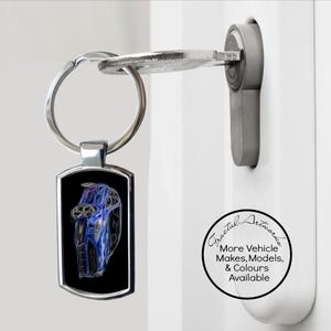 May include: A silver car keychain with a black background and a blue car design. The keychain is attached to a key in a white door. The keychain has the text "Fractal Artworks" and "More Vehicle Makes, Models, & Colours Available".
