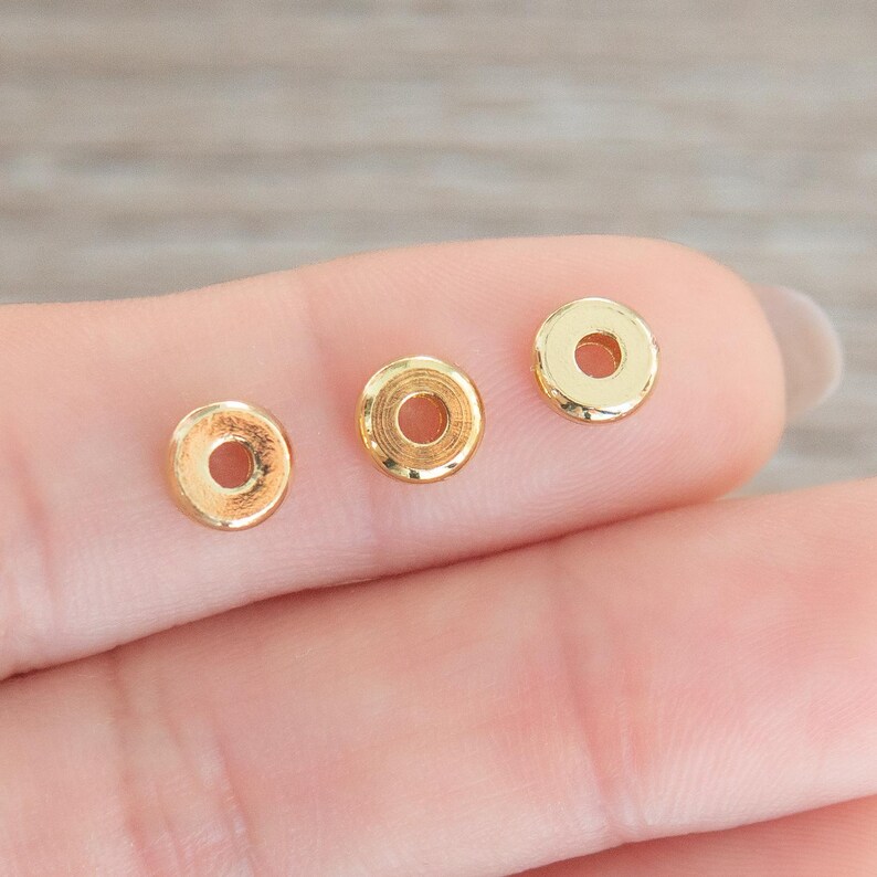 Puede incluir: Tres cuentas espaciadoras de metal de color dorado. Las cuentas son redondas con un agujero en el centro.