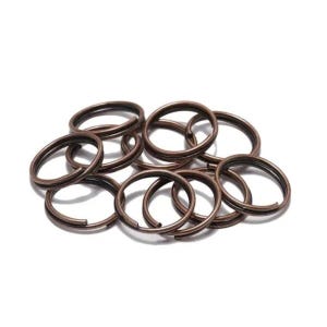 May include: A pile of 10 copper-colored key rings. The key rings are all the same size and are made of a thin metal.