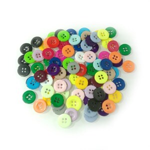 May include: A large assortment of colorful plastic buttons in various shapes and sizes. The buttons are arranged in a pile and are ready to be used for sewing or crafting projects.