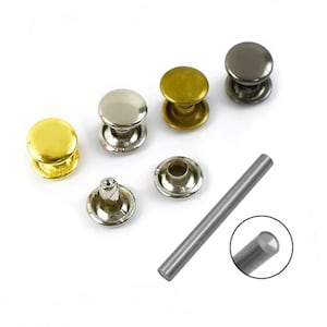 May include: A set of metal rivets in silver, gold, and black, with a tool for setting the rivets. The rivets are round with a raised centre and a flat base. The tool is a long, thin rod with a rounded end.