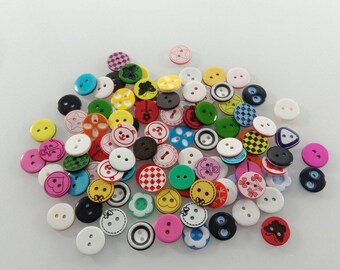 May include: A collection of colorful buttons in various sizes and designs. The buttons feature a range of colors, including pink, yellow, green, and black, with patterns like hearts, flowers, and geometric shapes. Some buttons have two holes, while others have four.