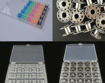 May include: A clear plastic storage box with 36 empty bobbins for sewing thread. The box is open and the bobbins are visible. There are also 20 silver metal bobbins in a pile.