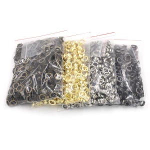 May include: Three bags of metal eyelets in black, gold, and silver. The eyelets are in clear plastic bags.