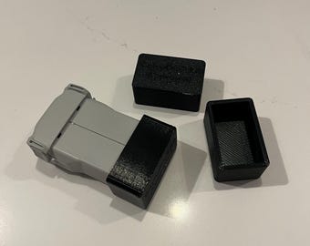 May include: Three small black plastic boxes with a gray plastic box with a black lid. The boxes are on a white surface.