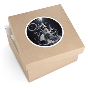 May include: A round sticker featuring a black and white illustration of a spooky house with a character standing on top. The house has a pointed roof and a large, round window. The character is holding a staff and has a large, round head. The sticker is on a brown cardboard box.