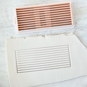 May include: A pink plastic tool with a grid of 12 parallel lines. The tool is used to create a textured pattern in clay. The tool is 4 mm wide.