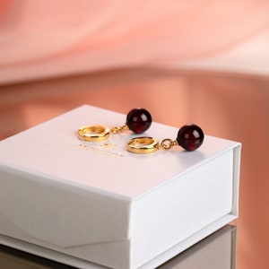 Cherry amber drop earrings with 24k gold vermeil huggie hoops on white Mondri logo jewelry box