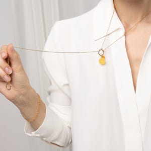 model wearing amber pendant with 24k gold vermeil bead chain in white outfit