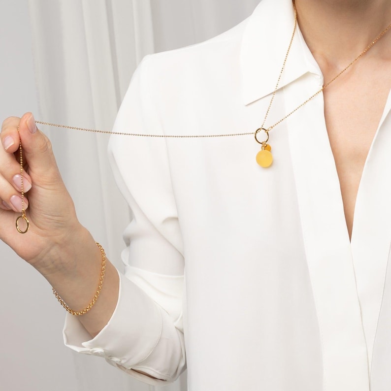 model wearing amber pendant with 24k gold vermeil bead chain in white outfit