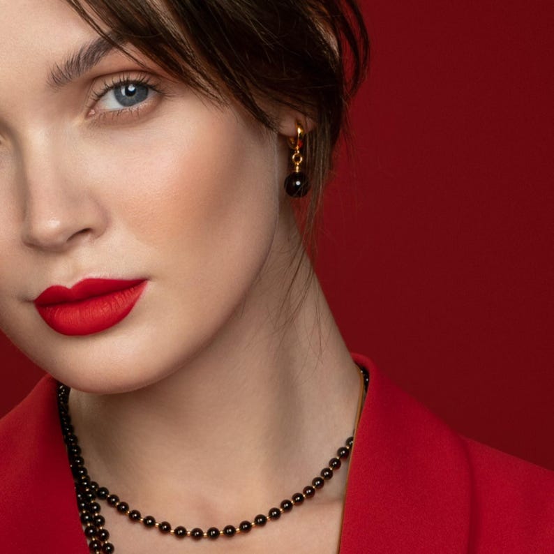 Woman wearing cherry amber earrings with red outfit