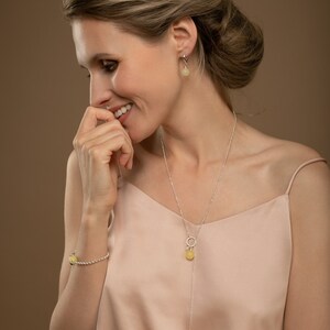 Model wearing lemon yellow matte amber pendant in 925 sterling silver with earrings and bracelet