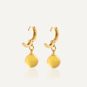 May include: Gold hoop earrings with a dangling yellow sphere charm.