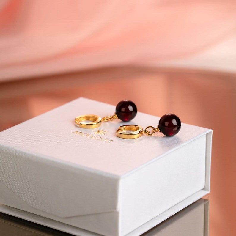 Cherry amber drop earrings with 24k gold vermeil huggie hoops on white Mondri logo jewelry box