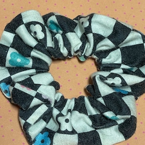 May include: A white and black checkered scrunchie with blue flower accents.
