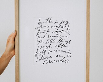 May include: A framed print with a handwritten quote that reads: "breathe in joy, embrace unknowns, look for adventures, find beauty in the little things, laugh often, fight for community, believe in miracles."