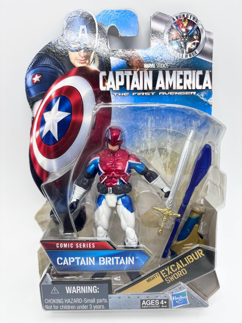 Pu&ograve; includere: Action figure di Captain Britain della serie Marvel Comics, confezionata su una carta blu e bianca. La figura indossa un costume rosso, bianco e blu e tiene in mano una spada d'argento. La confezione presenta Captain America e il testo "Captain America: The First Avenger".