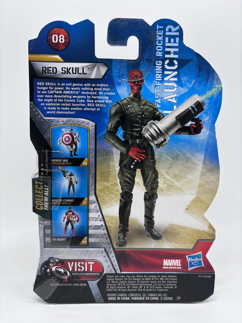 May include: Red Skull action figure on a Marvel branded card. The figure is in a combat pose, holding a silver and black rocket launcher. The card features text including "Red Skull" and "Fast-Firing Rocket Launcher."