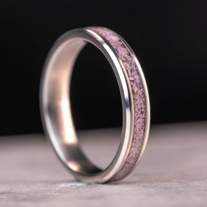 May include: A silver ring with a thin band of pink wood inlay.