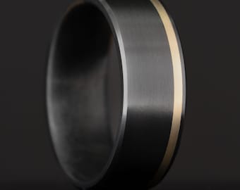 May include: A black ring with a thin gold band around the edge.