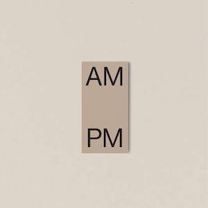 Op de afbeelding: Een rechthoekig, beige bord met de zwarte tekst "AM" bovenaan en "PM" onderaan. Het bord is gecentreerd tegen een lichtbeige achtergrond.