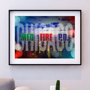 Puede incluir: Una impresión enmarcada de un paisaje urbano con la palabra "CHICAGO" en letras blancas grandes, con las palabras "MED", "FIRE" y "P.D." en letras más pequeñas superpuestas sobre el horizonte de la ciudad. La imagen tiene un fondo borroso y colorido.