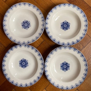 May include: Set of four white ceramic soup bowls with a blue and white floral design. The bowls have a scalloped edge and a floral pattern around the rim.