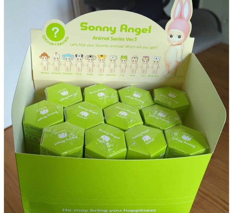 May include: A green and white box filled with small, hexagonal, green boxes. Each box has a white label with the text "Sonny Angel Animal 1" on it. The box is labeled "Sonny Angel Animal Series Ver.1" and has a picture of a pink bunny with a white dress on it.