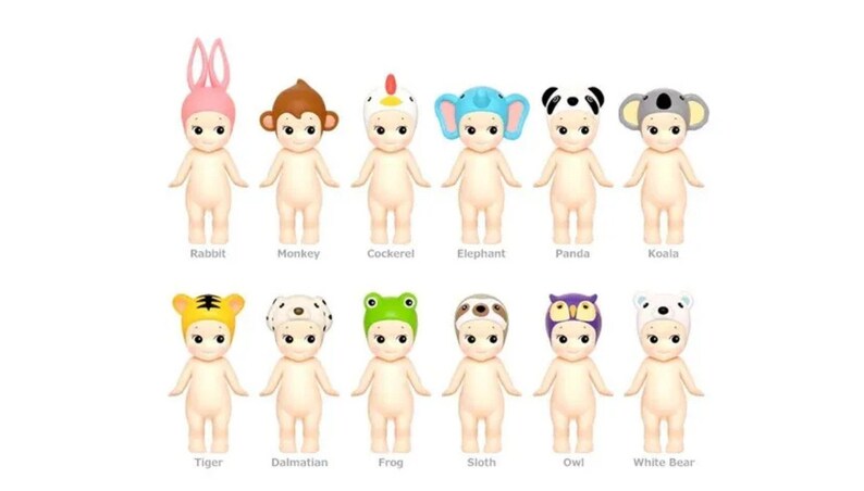 May include: A set of 12 adorable baby dolls wearing animal hats. The dolls are all nude-colored and have large, round eyes. The hats are a variety of colors and feature animals such as a rabbit, monkey, cockerel, elephant, panda, koala, tiger, dalmatian, frog, sloth, owl, and white bear.