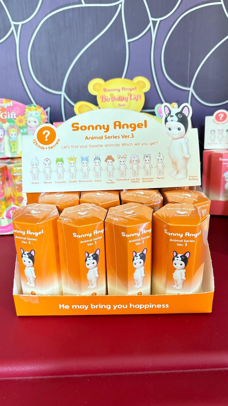 Pode incluir: Um expositor de caixas surpresa Sonny Angel Animal Series Ver. 3. Cada caixa apresenta um personagem animal diferente, incluindo um Bulldogue Franc&ecirc;s, uma Zebra, um Caniche Toy e um Chihuahua. As caixas s&atilde;o laranja e brancas com o logotipo Sonny Angel e o texto "Animal Series Ver. 3".