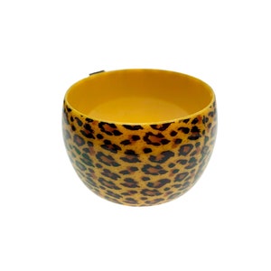 May include: A yellow ceramic cup with a leopard print design.