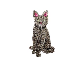 May include: A silver rhinestone cat brooch with pink rhinestones for the ears and eyes.