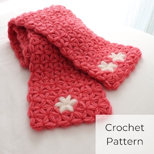 May include: A pink crocheted scarf with white crocheted flowers. Crochet Pattern.