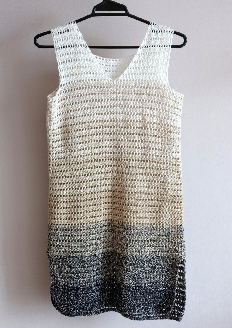 Op de afbeelding: Een wit gebreid jurkje zonder mouwen met een verloop van wit naar beige naar zwart.