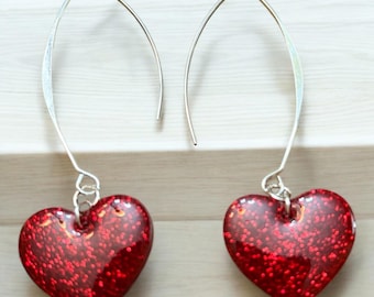 May include: A pair of silver dangle earrings with red glitter heart charms.