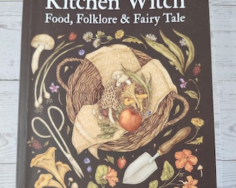 May include: A book titled Kitchen Witch: Food, Folklore & Fairy Tale by Sarah Robinson. The dark brown cover features a central illustration of a woven basket filled with mushrooms, an apple, and berries, surrounded by garden tools and flowers.