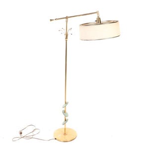 May include: A gold floor lamp with a white fabric shade and a decorative spiral design on the base.
