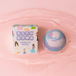 Może przedstawiać: Fioletowa, niebieska i biała bomba do kąpieli z nadrukiem kreskówkowej księżniczki na pudełku. Na pudełku widnieje napis "Bath Bomb Making Me Crazy".
