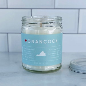 May include: A blue and white candle jar with a red heart and the text "ONANCOCK" on the label. The label also includes the text "BEST DAY EVER", "Phthalate Free", "Cotton Wick", "Small Batch", "Burn Time 30 hrs", "Soy Based", and "Batch 1450".