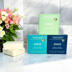 Könnte beinhalten: Drei Stück Naturseife mit den Worten "Rambling Caravan" und "Ohio, Home of Clean and Happy People" auf der Verpackung. Die Seife befindet sich in blauen, grünen und dunkelblauen Schachteln.
