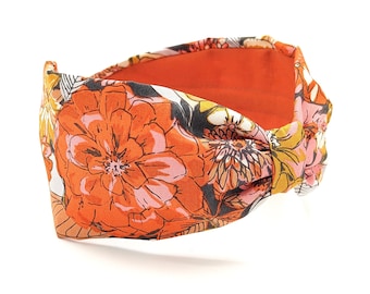 May include: A knotted headband with a floral print in shades of orange, pink, yellow, and black.