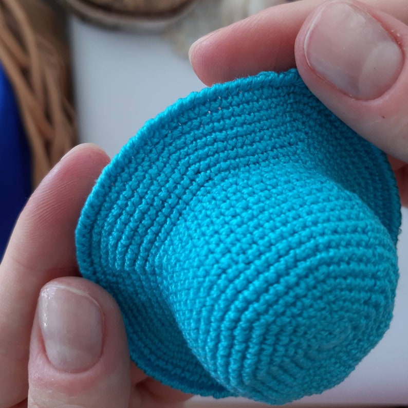 Pu&ograve; includere: Un piccolo cappello all'uncinetto di colore turchese brillante.