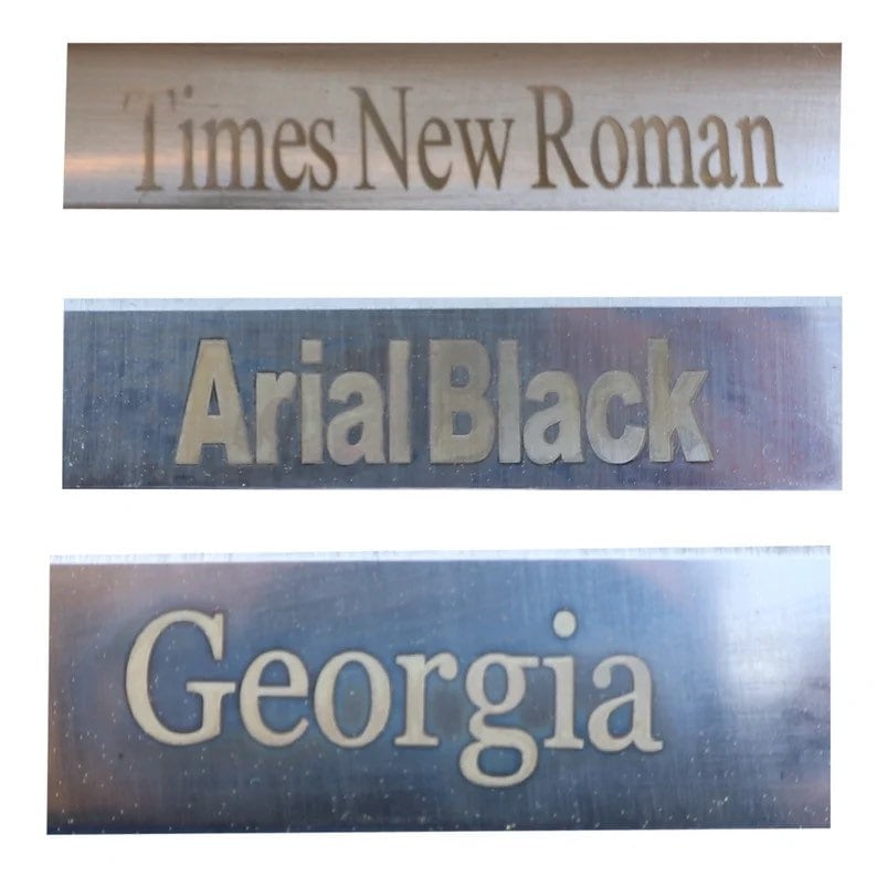 Może przedstawiać: Trzy metalowe płytki z wygrawerowanymi na nich r&oacute;żnymi czcionkami. G&oacute;rna płytka zawiera napis "Times New Roman", środkowa płytka zawiera napis "Arial Black", a dolna płytka zawiera napis "Georgia".
