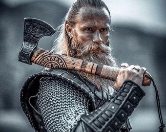 May include: A man with a long, braided beard and long hair is wearing a chainmail shirt and leather armor. He is holding a large axe with a wooden handle and a metal head. The axe has intricate carvings on the handle.