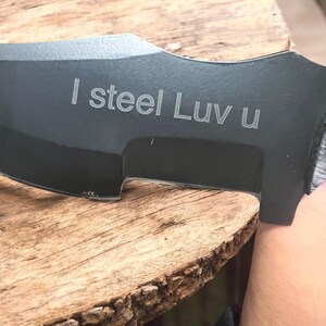 Może przedstawiać: Czarny n&oacute;ż z zakrzywionym ostrzem i rękojeścią. Na ostrzu wygrawerowano słowa "I steel Luv u".